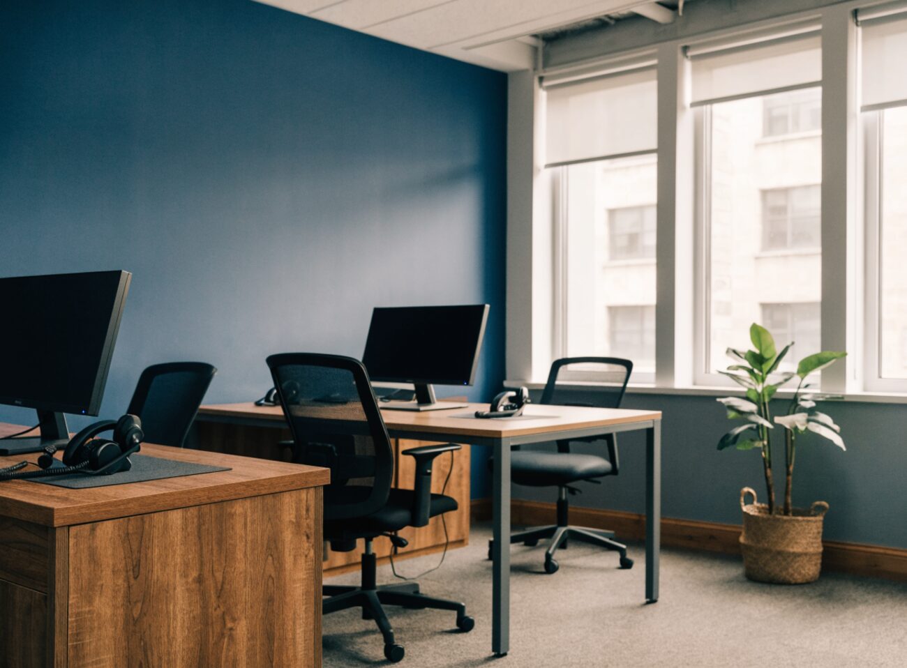 A clean, well-run small outbound operations room with tidy desks, monitors, and telephone headsets